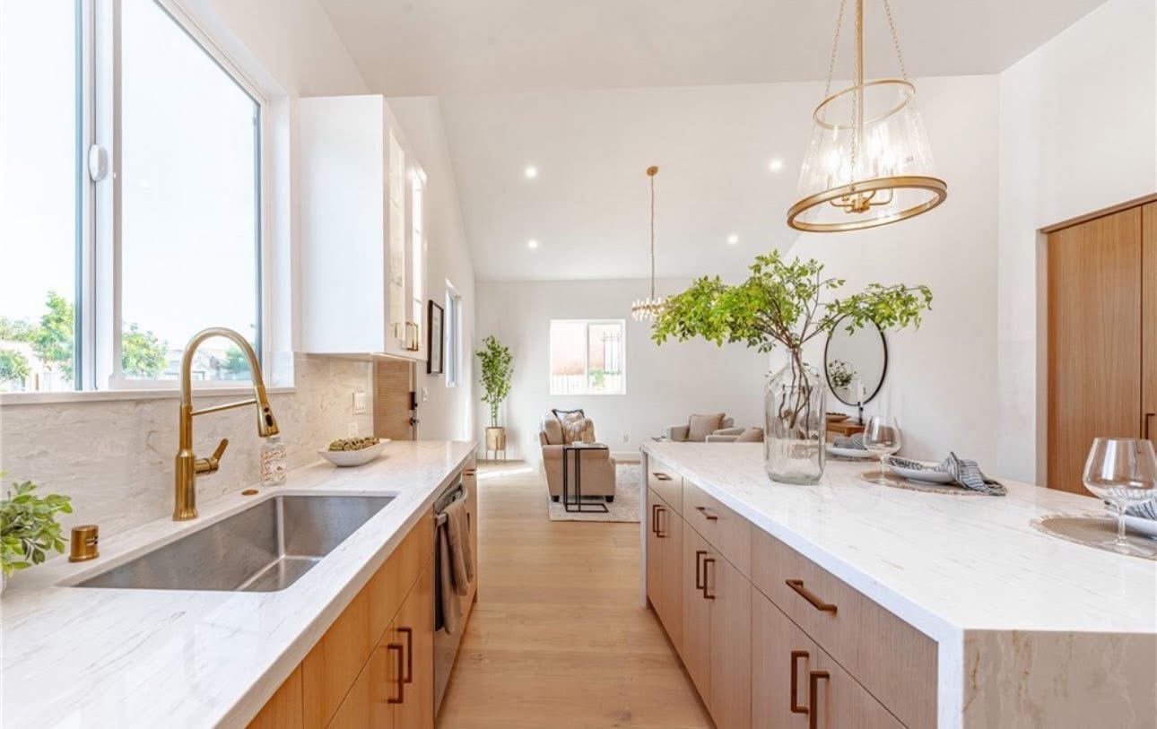 Open concept kitchen remodel with white oak cabinets, brass fixtures and waterfall quartz island in Los Angeles