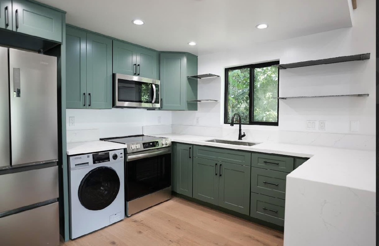 ADU kitchen interior — green shaker cabinets, quartz countertops, washer, wood floors