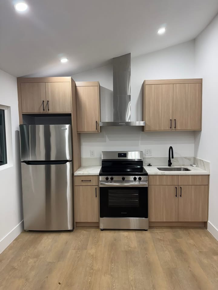 ADU kitchen — light maple cabinets, stainless range, hood, marble countertops