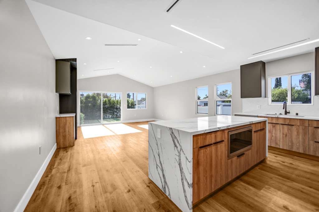 Modern kitchen remodel with wood grain island, waterfall countertop and vaulted ceiling LED lighting Orange County contractor