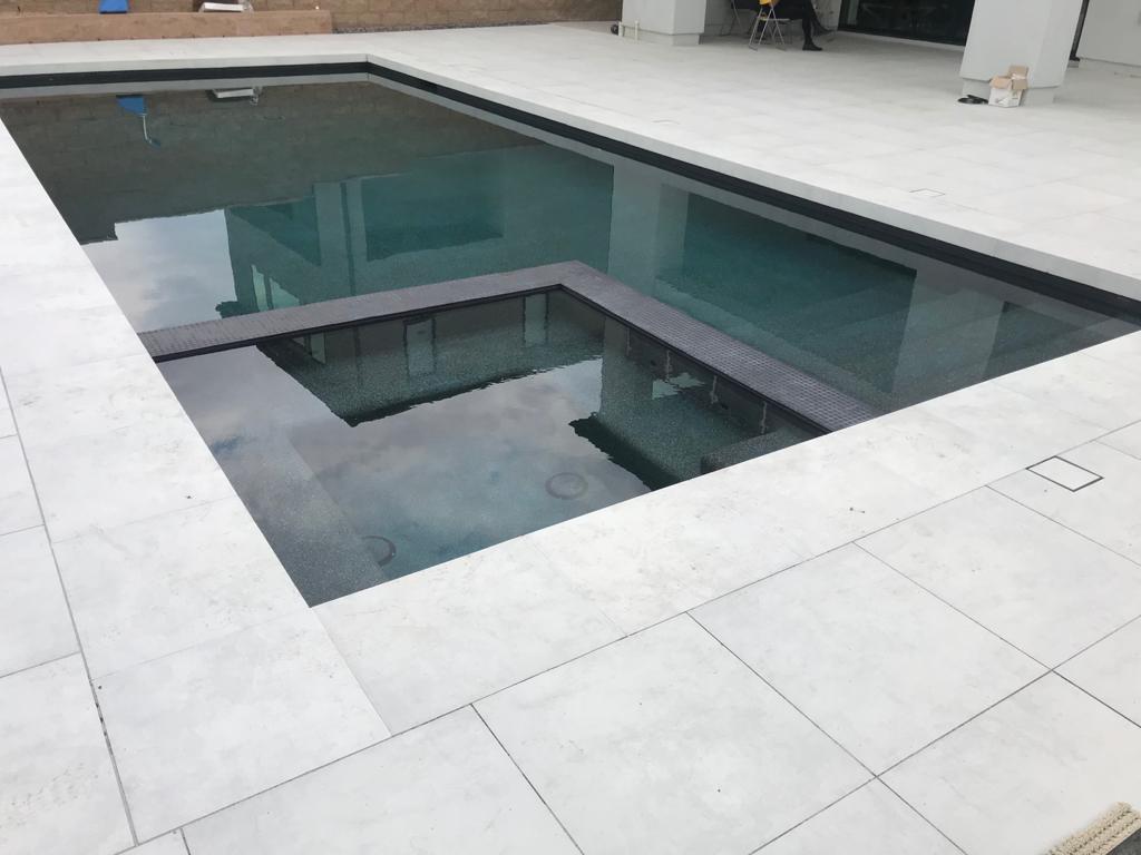Modern large-format porcelain paver pool deck with a rectangular spa and clean-lined coping