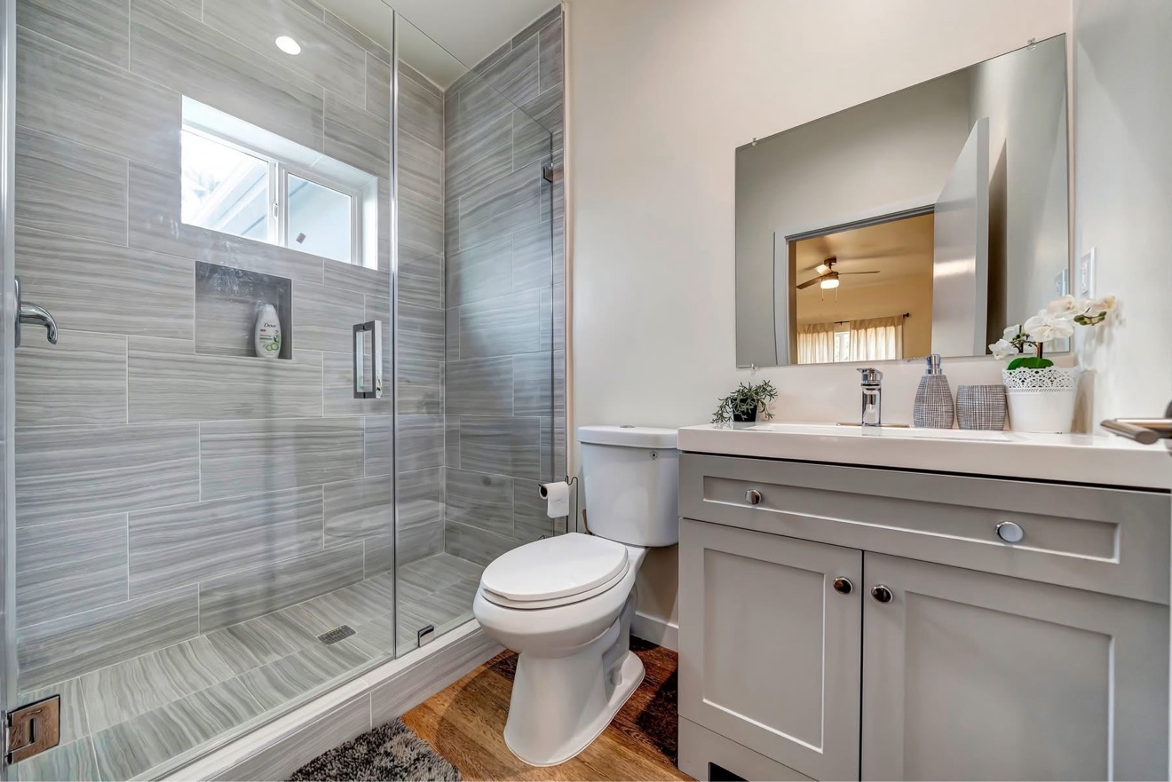 Finished bathroom with walk-in shower, frameless glass, linear drain and shaker vanity — home addition in Costa Mesa